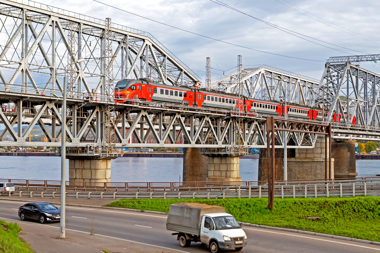 Городская электричка идет по железнодорожному мосту